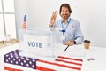 Handsome middle age man sitting at voting stand showing and pointing up with fingers number three while smiling confident and