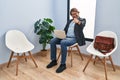 Handsome middle age man sitting at waiting room working with laptop pointing to you and the camera with fingers, smiling positive Royalty Free Stock Photo