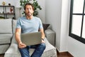 Handsome middle age man using computer laptop on the sofa making fish face with lips, crazy and comical gesture Royalty Free Stock Photo