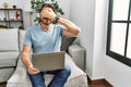 Handsome middle age man using computer laptop on the sofa smiling and laughing with hand on face covering eyes for surprise Royalty Free Stock Photo