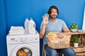 Handsome middle age man waiting for laundry showing and pointing up with fingers number four while smiling confident and happy