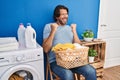 Handsome middle age man waiting for laundry very happy and excited doing winner gesture with arms raised, smiling and screaming