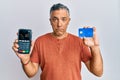 Handsome middle age mature man holding dataphone and credit card depressed and worry for distress, crying angry and afraid Royalty Free Stock Photo