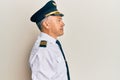 Handsome middle age mature man wearing airplane pilot uniform looking to side, relax profile pose with natural face and confident