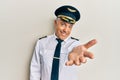 Handsome middle age mature man wearing airplane pilot uniform smiling cheerful offering palm hand giving assistance and acceptance Royalty Free Stock Photo