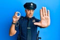 Handsome middle age mature man wearing police uniform holding metal handcuffs with open hand doing stop sign with serious and Royalty Free Stock Photo