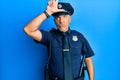 Handsome middle age mature man wearing police uniform making fun of people with fingers on forehead doing loser gesture mocking
