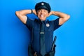 Handsome middle age mature man wearing police uniform relaxing and stretching, arms and hands behind head and neck smiling happy Royalty Free Stock Photo