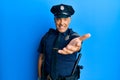 Handsome middle age mature man wearing police uniform smiling cheerful offering palm hand giving assistance and acceptance Royalty Free Stock Photo