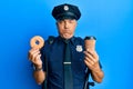 Handsome middle age mature police man eating donut and drinking coffee puffing cheeks with funny face Royalty Free Stock Photo