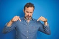 Handsome middle age senior man with grey hair over isolated blue background Pointing down looking sad and upset, indicating Royalty Free Stock Photo