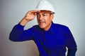 Handsome middle age worker man wearing uniform and helmet over isolated white background very happy and smiling looking far away Royalty Free Stock Photo