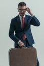 Handsome middle aged businessman holding luggage and fixing glasses