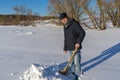 Handsome middle-aged caucasian man cleans snow on household plot