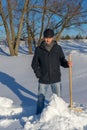 Handsome middle-aged caucasian man cleans snow on household plot