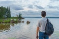 Handsome middle-aged man with backpack standing on bay shore in summer evening. Tourist on the beautiful landscape background. Royalty Free Stock Photo