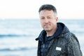 Handsome middle-aged man at the beach. Attractive happy smiling mid adult male model posing at seaside, sunset o sunrise. Outdoor Royalty Free Stock Photo