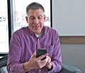 Handsome middle aged man in casual clothes is using a smart mobile cell phone. Royalty Free Stock Photo