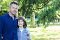 Handsome middle-aged man in park with his son. Attractive mid adult male model posing spring outddor with teen boy Royalty Free Stock Photo