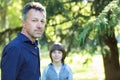 Handsome middle-aged man in park with his son. Attractive mid adult male model posing outddor with teen boy Royalty Free Stock Photo