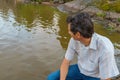 Handsome middle-aged man sitting on bay shore in summer evening Royalty Free Stock Photo