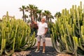 Handsome middle-aged man takes a selfie in front of a large cactus in an exotic seaside resort