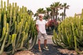 Handsome middle aged man using smartphone in front of a large cactus in an exotic seaside resort