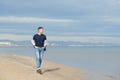 Handsome middle-aged man walking at the beach. Attractive happy smiling mid adult male model posing at seaside in blue jeans, t- Royalty Free Stock Photo