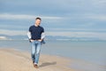 Handsome middle-aged man walking at the beach. Attractive happy smiling mid adult male model posing at seaside in blue jeans, t- Royalty Free Stock Photo