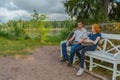 Handsome middle-aged man and young pretty lady sitting on bench Royalty Free Stock Photo