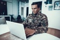 Handsome Military Man Works at Table on Laptop