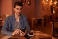 Handsome millenial in restaurant with cellphone