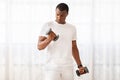 Handsome millennial black man doing dumbbell workout at home,