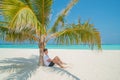 Handsome model man in stylish clothes relaxing under palm tree at tropical sandy beach at island luxury resort Royalty Free Stock Photo