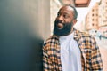 Handsome modern african american man with beard smiling positive leaning over wall