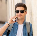 Handsome modern happy young man talking on his smart phone outsi Royalty Free Stock Photo