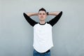 Handsome modern young man with a fashionable hairstyle in a stylish black and white t-shirt in vintage jeans poses Royalty Free Stock Photo