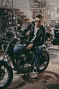 handsome motorcyclist in sunglasses and black leather jacket with classic motorbike
