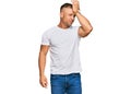 Handsome muscle man wearing casual white tshirt surprised with hand on head for mistake, remember error