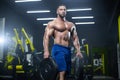 Handsome muscular athlete man is standing in a gym holding barbell discs in both hands Royalty Free Stock Photo