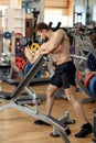 Handsome muscular athletic young man bodybuilder fitness model exercise biceps with dumbbell on the bench in gym. Royalty Free Stock Photo