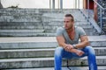 Handsome muscular blond man sitting on stair steps Royalty Free Stock Photo