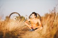 A handsome muscular guy with a naked torso sitting near a bicycle in the countryside in a field resting, listening to music and ho Royalty Free Stock Photo