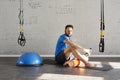 Handsome muscular man athlete sitting in sunny sport club, relaxed after workout, holding bottle of water in hands. Space for text Royalty Free Stock Photo