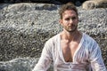 Handsome muscular man on the beach laying on gravel Royalty Free Stock Photo