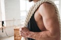 Handsome muscular man holding on shoulder rope workout in light gym