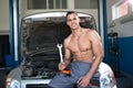 Handsome muscular mechanic with a tool