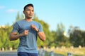 Handsome muscular sporty man jogging in the park on a sunny day. Healthy lifestyle concept.