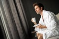 Handsome, muscular, young man drinking his morning coffee in a hotel room Royalty Free Stock Photo