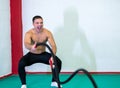 A handsome muscular young man using battle ropes for exercise in a gym. He focuses on performing the exercise, screams. Royalty Free Stock Photo